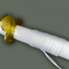 Détail du manche du katana Ame no Habakiri, avec un cordage blanc soigneusement enroulé et une garde dorée en forme de fleur, sur un fond gris neutre.